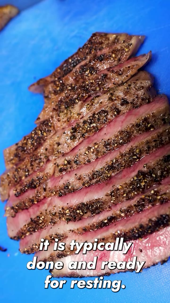 Pepper-crusted steak sliced on a blue board